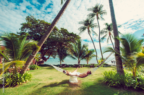 On a hammock in the tropics . Relaxing in hammock on tropical beach .