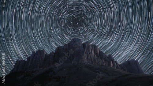 Beautiful star trails time-lapse over the rocky mountains. Polar North Star at the center of rotation. 4K resolution.