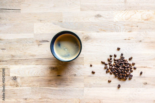 espresso coffee in a blue cup and some coffee grain on a raw oak table