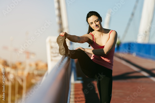 Young fitnesswoman runner stretching legs after run. photo