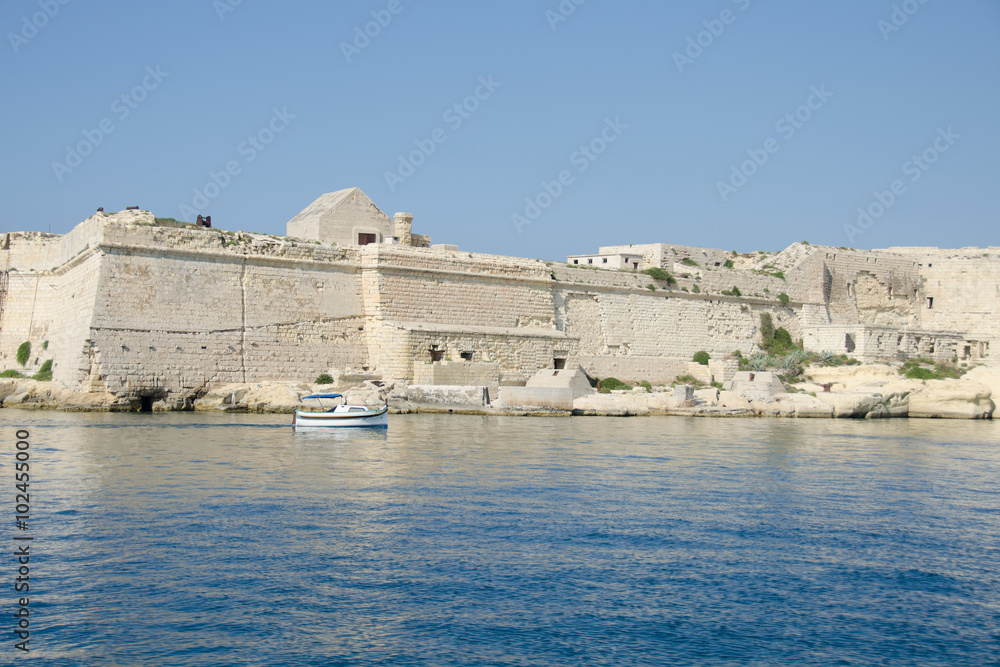 A small boat sails past the walls of the ancient city