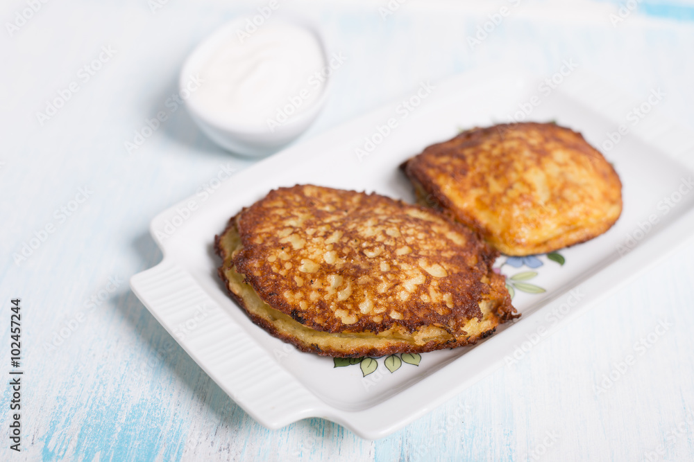 Potato pancakes with meat and sour cream in Belarusian style on light background Potato pancakes with meat and sour cream in Belarusian style on light background