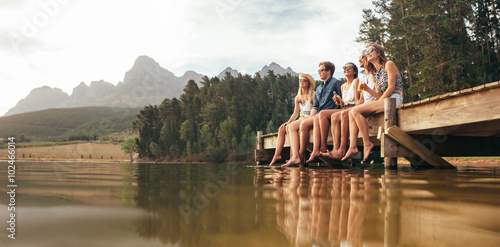 Canvas Print Friends sitting on pier at lake drinking beers