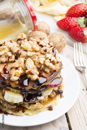 Pancakes with banana , walnut & chocolate on wood background