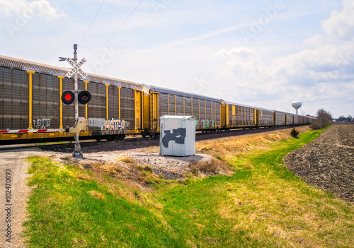 Wide angle view of freight train passing at railroad grade crossing with signal