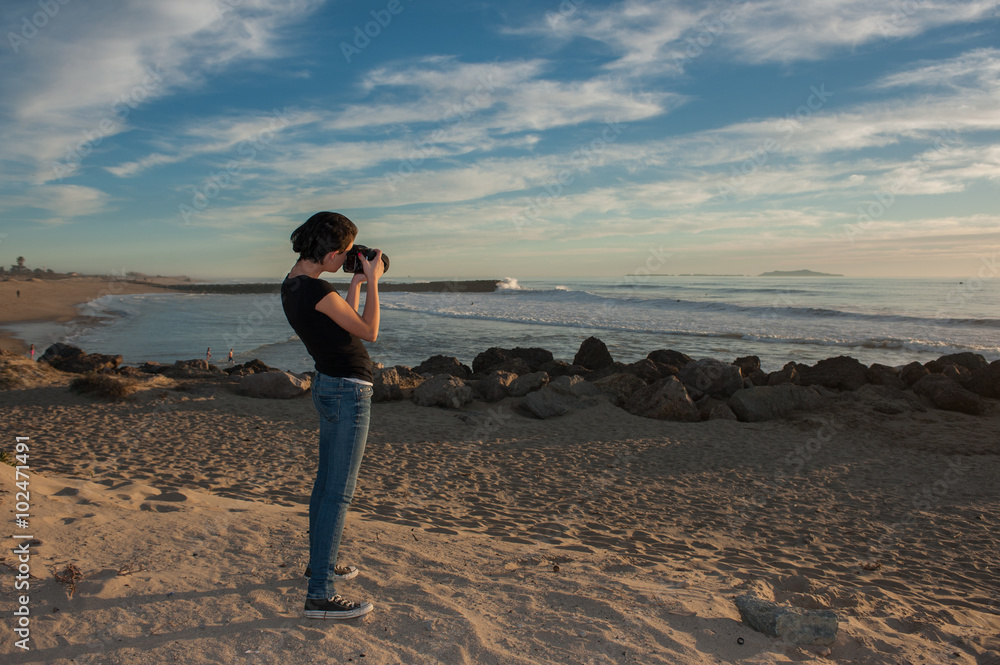 Female teen photographer pointer her camera at the beach. Female teen photographer pointer her camera at the beach.