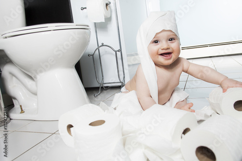 Toddler ripping up toilet paper in bathroom