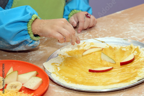 child preparing fruit pizza closeup