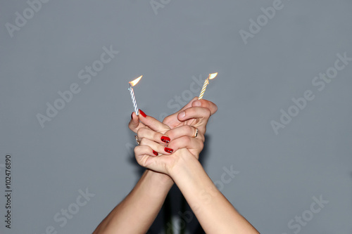 two candles burning in the hands