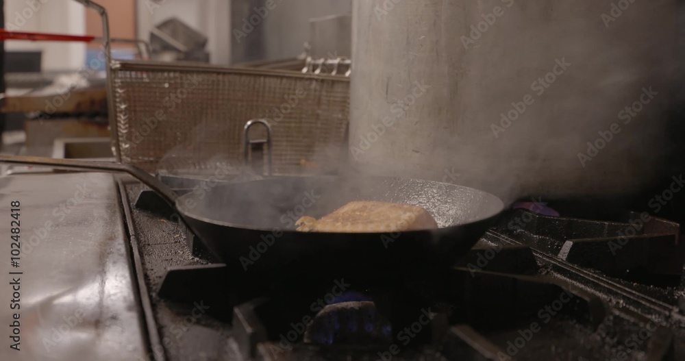 Salmon cooks over a gas stove in a professional kitchen. Salmon cooks over a gas stove in a professional kitchen.