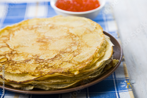 Pancakes with red caviar on a table.