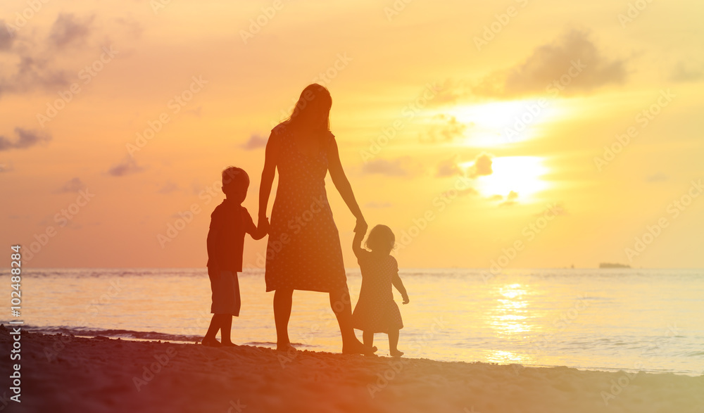 mother and two kids walking on beach at sunset