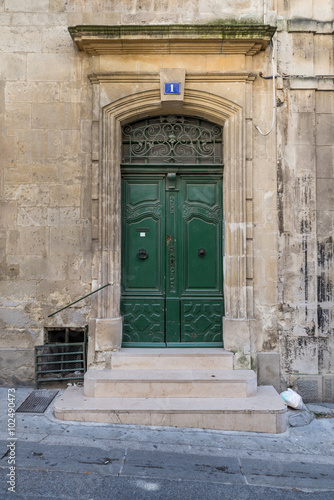 Od gate with ornaments and closed green doors in an old building in a street in Arles, France on a sunny day in the summer © Roen