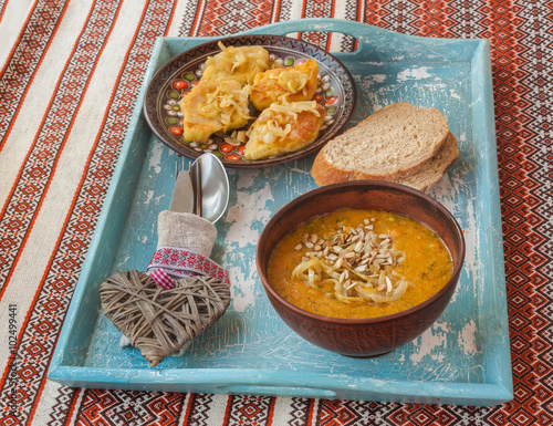 Potato rhombuses with fried onions and pumpkin soup on the tray photo