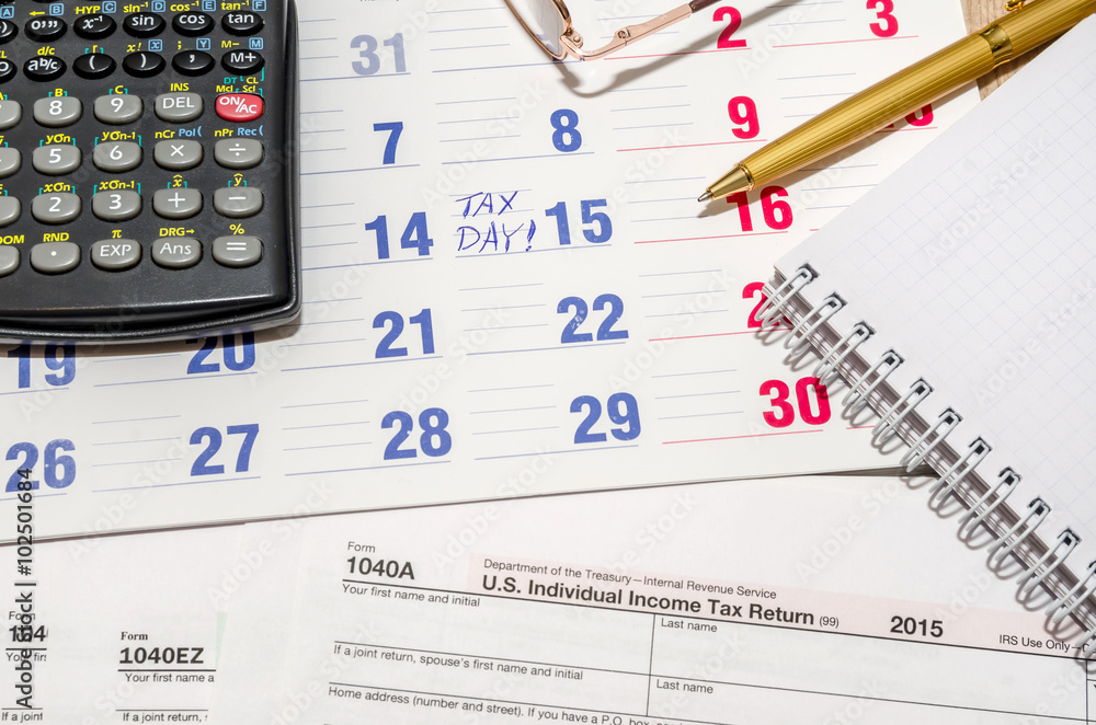 tax form with calculator, pen, notepad above paper calendar tax form with calculator, pen, notepad above paper calendar