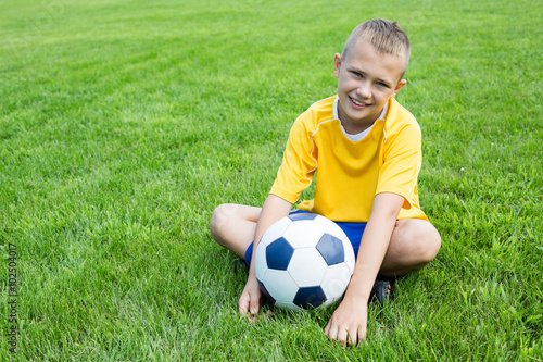 Boy football player with the ball is sitting on the football fie © Stanislav Komogorov