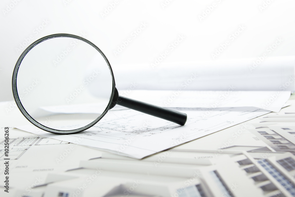 Architectural blueprints, blueprint rolls and magnifying glass on white background. Architectural blueprints, blueprint rolls and magnifying glass on white background.