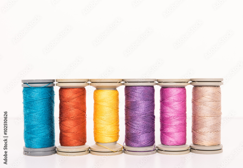 Multi-colored threads, sewing kit, a set of tailor on white background Multi-colored threads, sewing kit, a set of tailor on white background