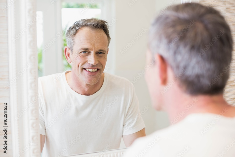 Obraz premium Handsome man looking at himself in the mirror