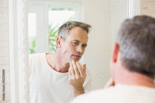 Handsome man looking at himself in the mirror