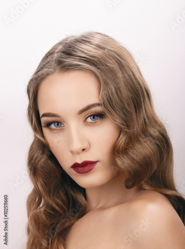 Closeup portrait of young fashionable blonde woman with wavy hairstyle showing gorgeous vintage makeup 