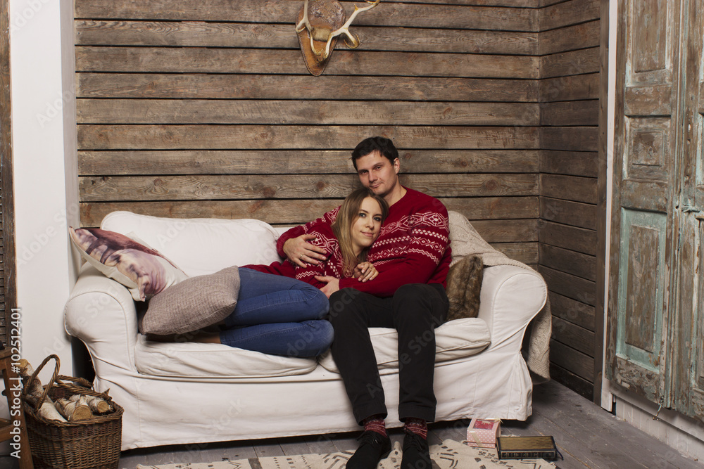 Obraz premium a beautiful couple. a love story, celebrating the New Year's holiday, Christmas and Valentine's Day. In the background christmas attributes: Christmas tree and gifts.
