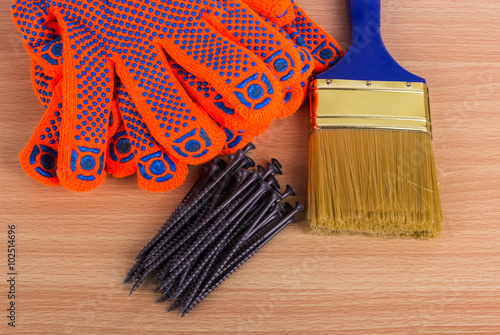 Building objects on wooden background: paint brush, gloves and n