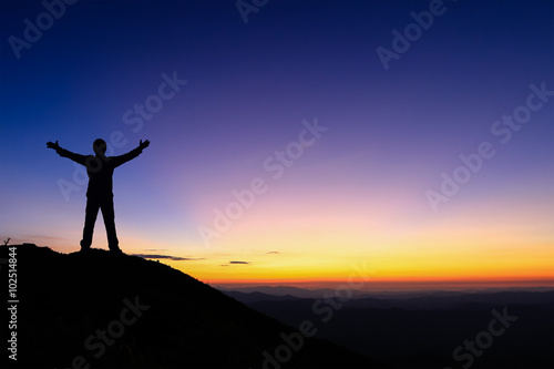 Silhouette of man standing and spread hand on the top of mountain