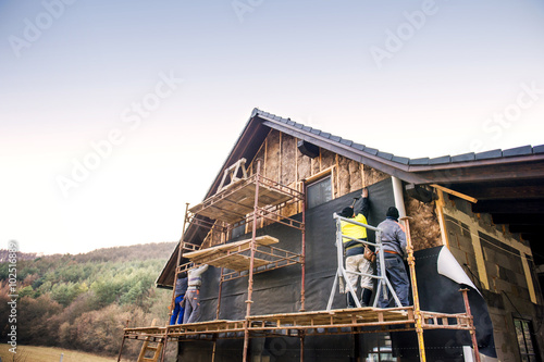 Construction workers thermally insulating house with glass wool and foil. © Halfpoint