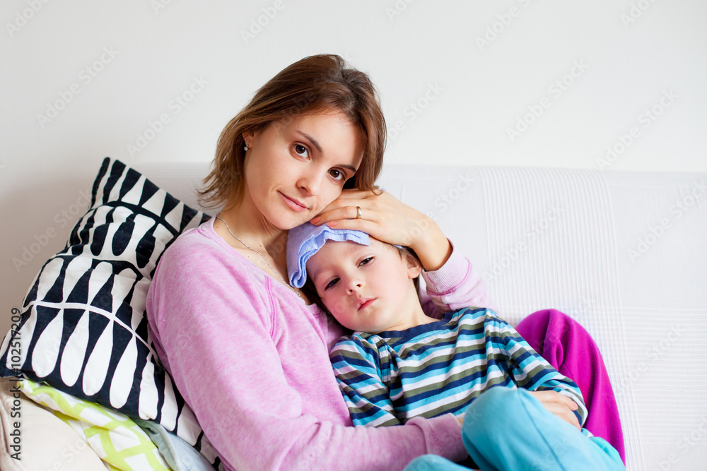 Young mother, holding her little sick boy, wet cloth on his fore Young mother, holding her little sick boy, wet cloth on his fore