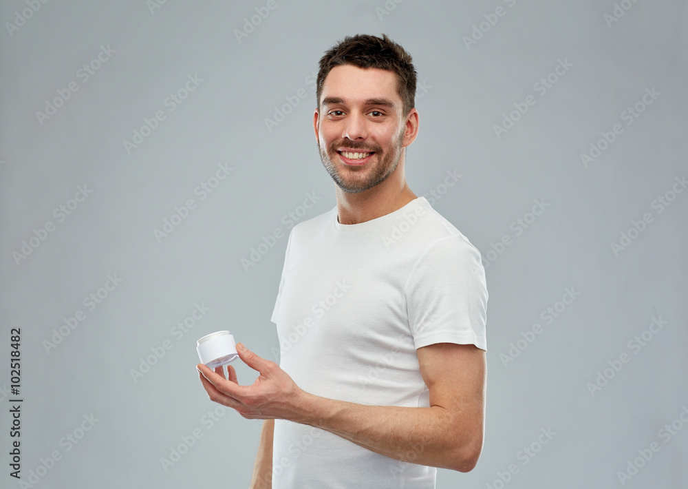 happy young man with cream jar over gray happy young man with cream jar over gray
