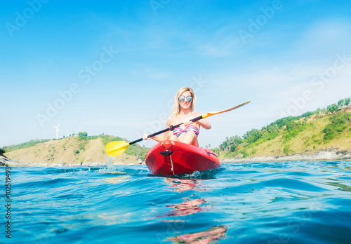 Woman exploring calm tropical bay by kayak.