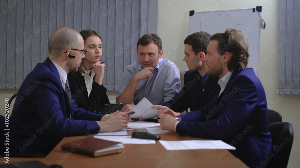 The team of young businesspeople. They work together with the documents and figures. In the office. The team of young businesspeople. They work together with the documents and figures. In the office.