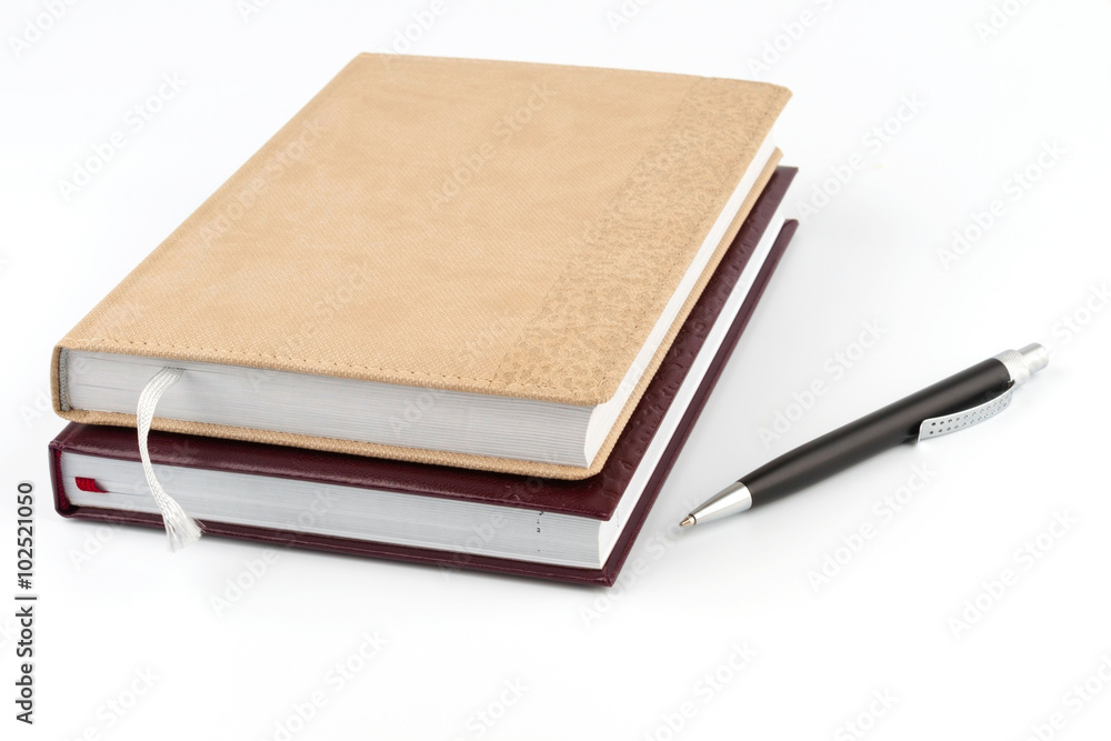 Two diary stacked lying next to a black pen. Two diary stacked lying next to a black pen.