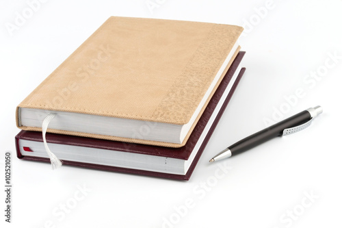 Two diary stacked lying next to a black pen.