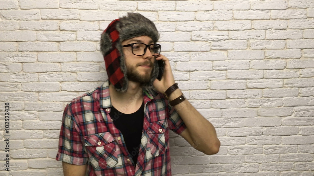 man smart phone call, smile guy hipster talking fashion style wearing hat glasses over white brick wall man smart phone call, smile guy hipster talking fashion style wearing hat glasses over white brick wall