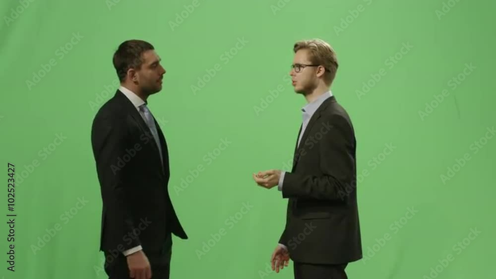Two businessmen in suits are having a conversation on a mock-up green screen in the background. Shot on RED Cinema Camera. Two businessmen in suits are having a conversation on a mock-up green screen in the background. Shot on RED Cinema Camera.