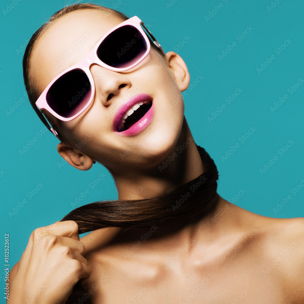 Portrait of beautiful young girl in sunglasses smiling in studio on a ...