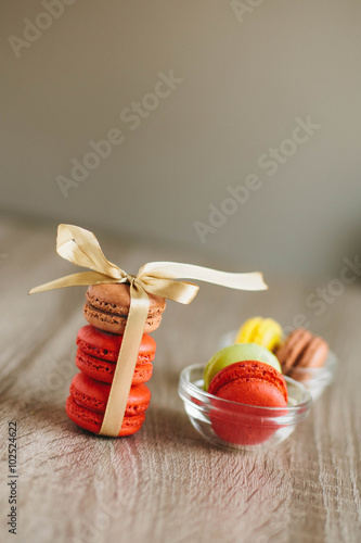 Macaroons on the wooden table with golden ribbon.