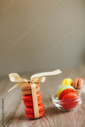 Macaroons on the wooden table with golden ribbon.
