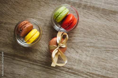 Macaroons on the wooden table with golden ribbon.