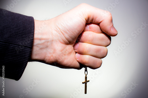Hand holds a chain with gold crucifix photo