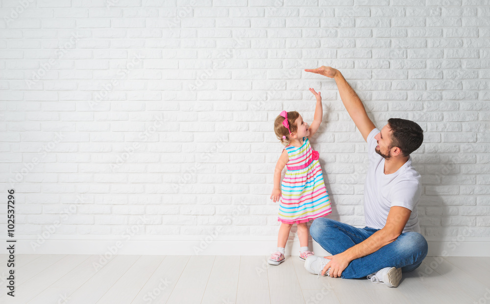 concept. Dad measures growth of her child daughter at a wall - obrazy, fototapety, plakaty 