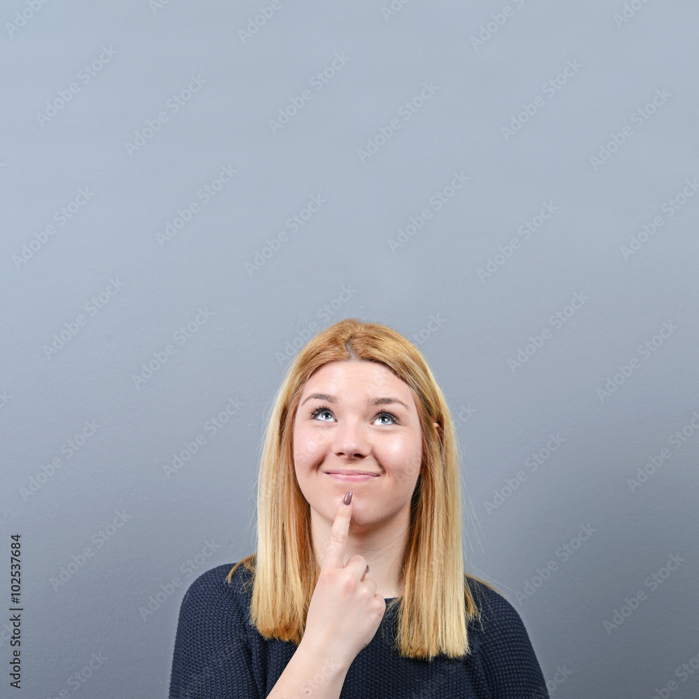 Fototapeta premium Portrait of woman coming up with an idea against gray background