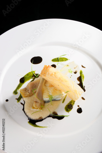 Fine dining, baked cod fillet with spinach sauce and roasted onions