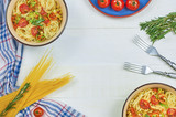 Spaghetti with vegetables on a plate. Serving on a white wooden table. An Italian-American dish. Horizontal top view, rustic style. Selective focus.