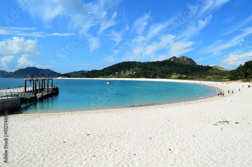 General view of a beautiful semicircular beach  Playa de Rodas  in the Cies Islands. It can be seen the pier and unidentified people.    