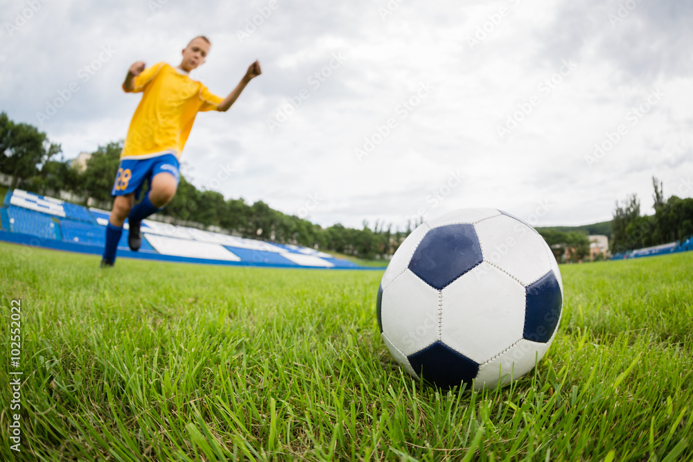 Obraz premium Boy playing football at the stadium. Natural lawn.