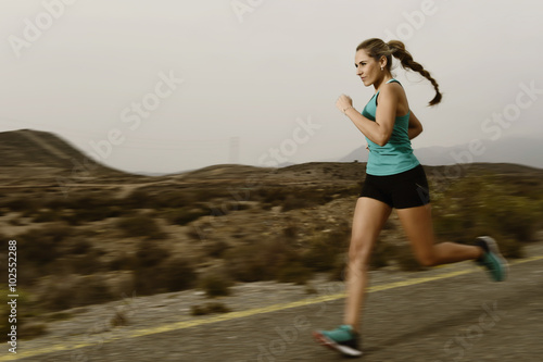 young fit sport woman running outdoors on asphalt road in mountain fitness workout