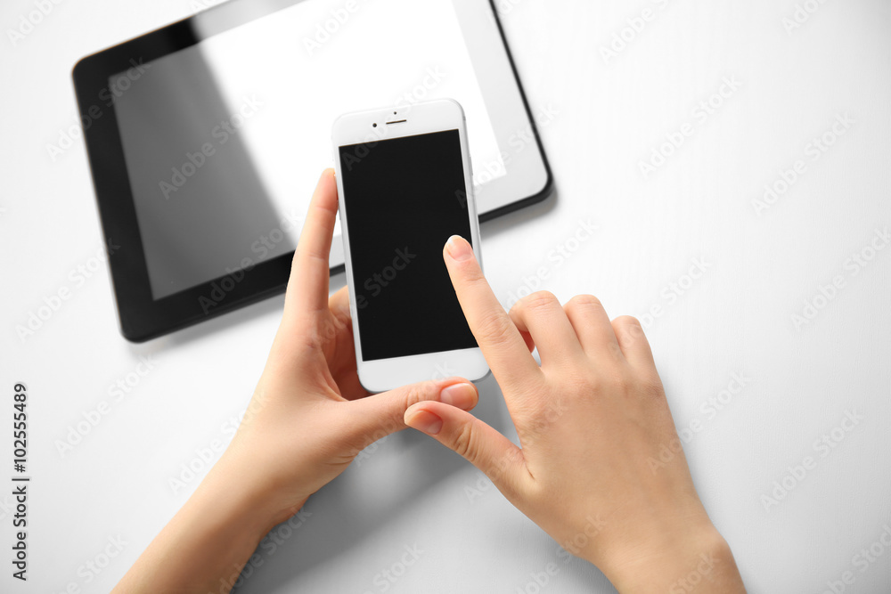 A tablet and female hands using mobile phone, isolated on white